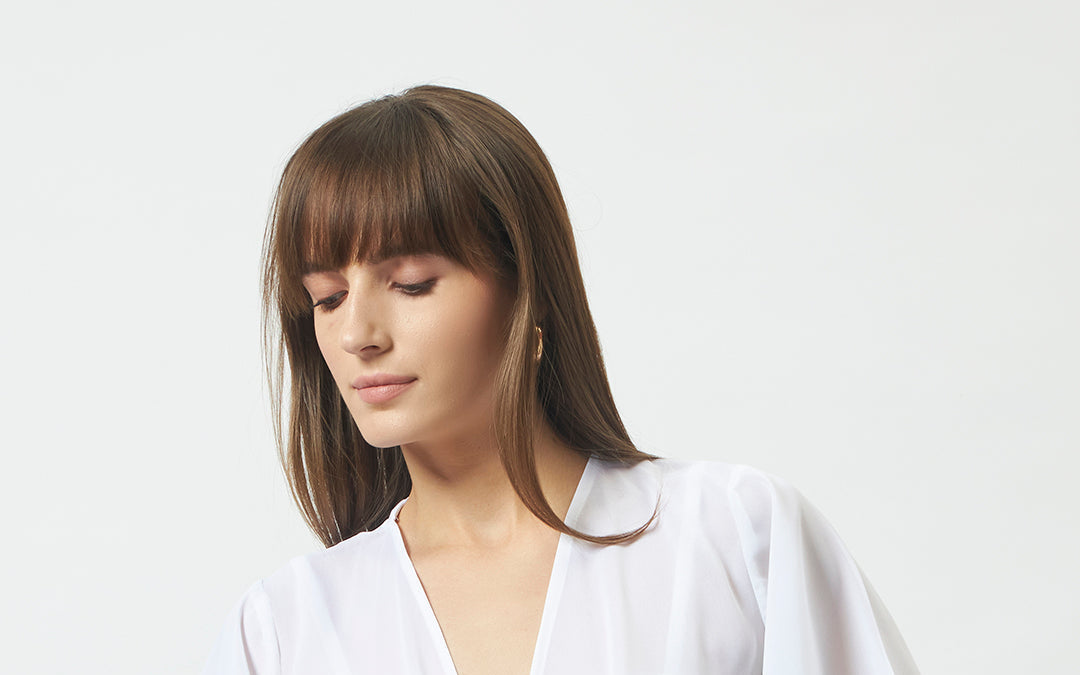 An off-white waterfall crop shrug worn open — the most versatile layering piece in the wardrobe